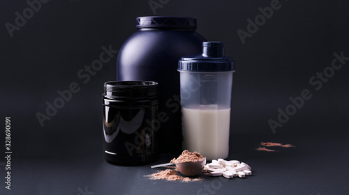 Sports nutrition supplements on a black background. Fitness, bodybuilding, healthy lifestyle concept. Whey protein powder in measuring scoop. Copy space photo