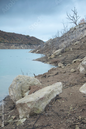 Pantano de Rialb medio vacío de agua con rocas y arboles secos (Cataluña, España). photo