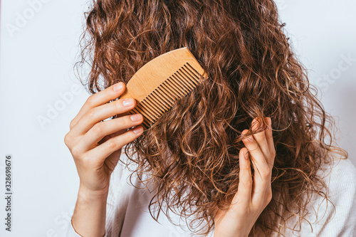 Close-up young woman combing her curly hair photo