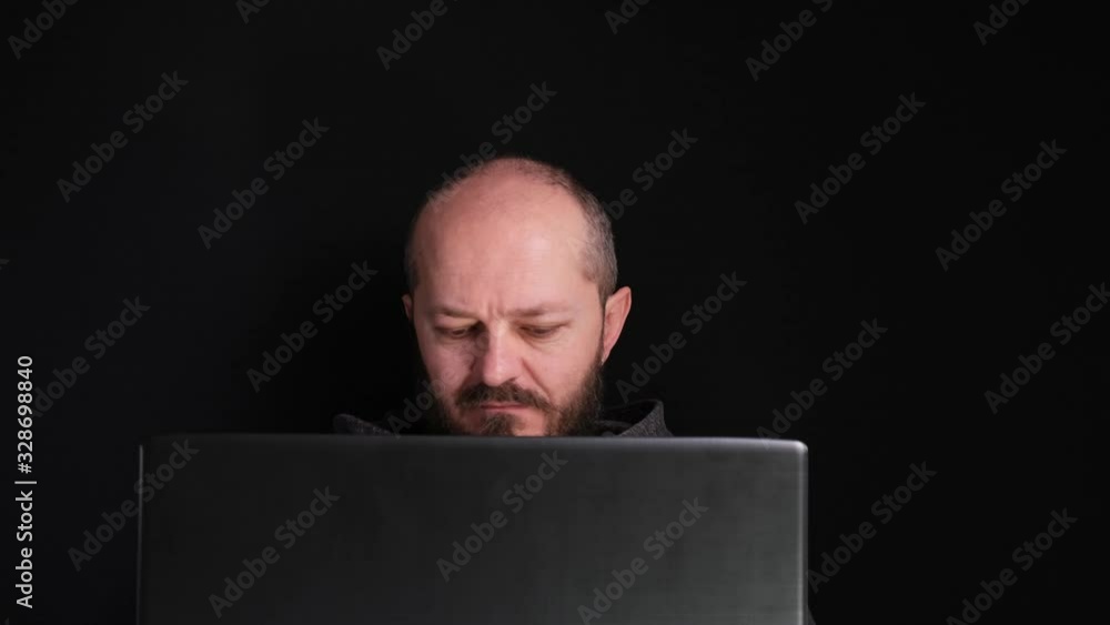 Caucasian adult man in hoodie sitting behind the laptop and working, black background. Home office concept. Head and shoulders.
Caucasian adult man in hoodie sitting behind the laptop and working, black background. Home office concept. Head and shoulders.