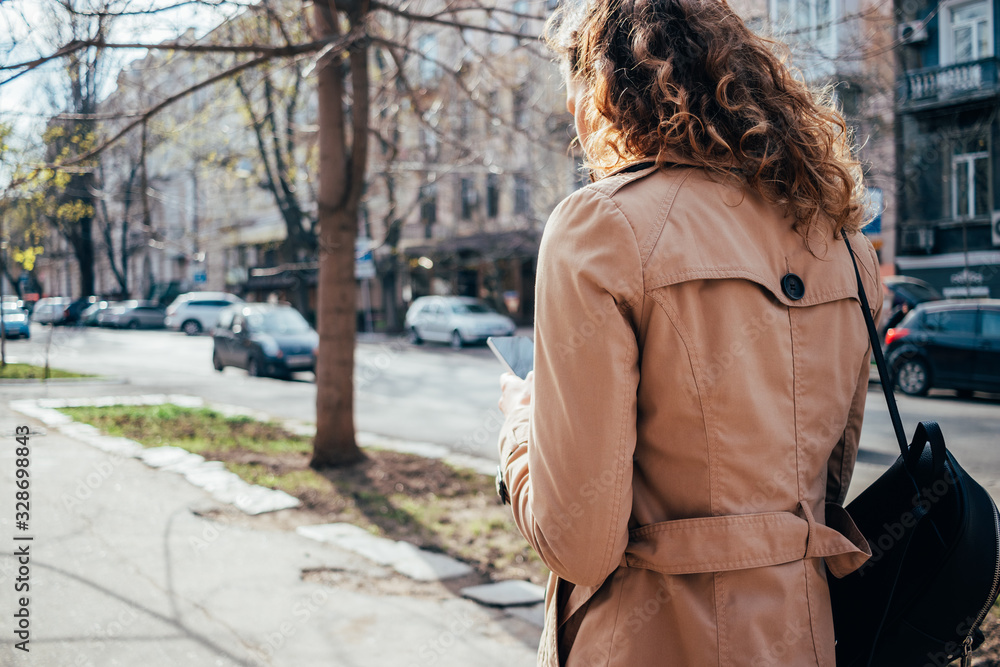 Female wearing beige coat typing text messages on mobile device Female wearing beige coat typing text messages on mobile device