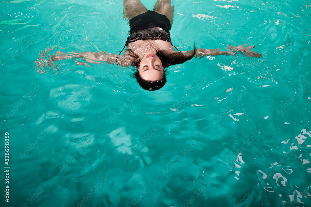 beautiful girl is relaxing in the Spa pool,swim and relax. young woman floating in water on the back,