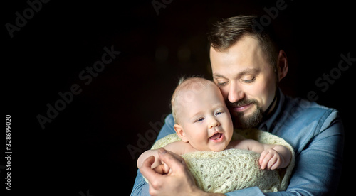 A happy father lives in the arms of a newborn baby, hugs and poses creamly. Paternity