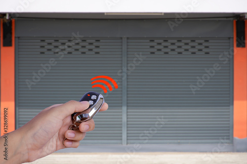 Foto Hand using remote control to open the automatic shutter roller steel garage gate