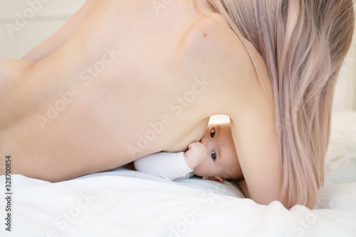 Woman breastfeeding newborn baby. Mother breastfeeding newborn boy lying in bed. Concept breast feeding. Baby eating mother's milk. Young woman nursing and feeding baby. Concept of lactation infant. photo