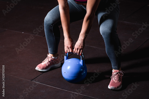 Young sweaty strong muscular fit girl hands holding heavy kettlebell on the floor concentrating and preparing for hardcore cross swing workout training in the gym selective focus © Srdjan