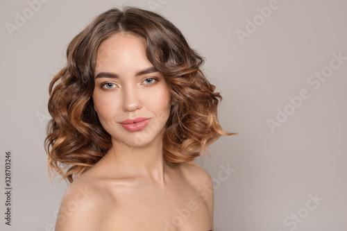 Portrait of a young smiling woman. Voluminous wavy hair. on white background