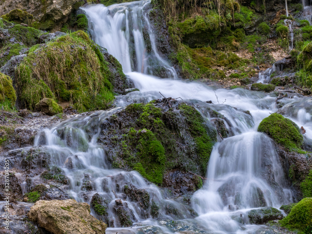 A stream of water flowing over rocks and creating a waterfall effect. A stream of water flowing over rocks and creating a waterfall effect.