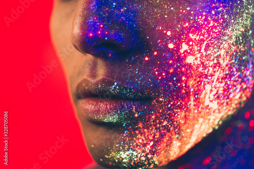 Handsome boy dancing at the rave party with fluorescent paintings on his face