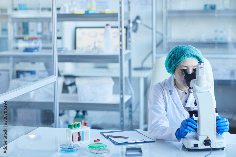 Horizontal shot of chemical industry worker sitting alone in modern laboratory using microscope, copy space Horizontal shot of chemical industry worker sitting alone in modern laboratory using microscope, copy space