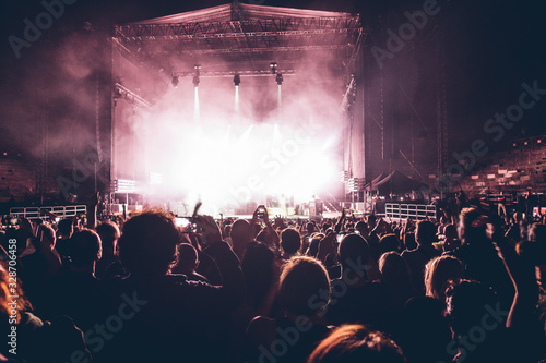 people silhouettes at the music concert. Crowd and fans showing love for the rock band at the festival