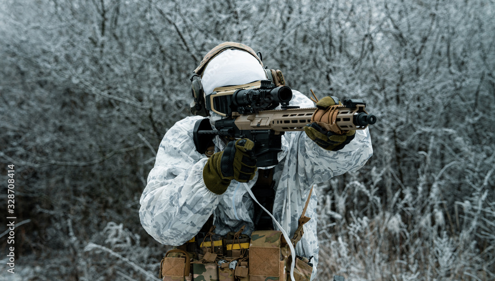 Fototapeta premium Closeup military man in white camouflage uniform with machinegun. Soldier aims of the machinegun