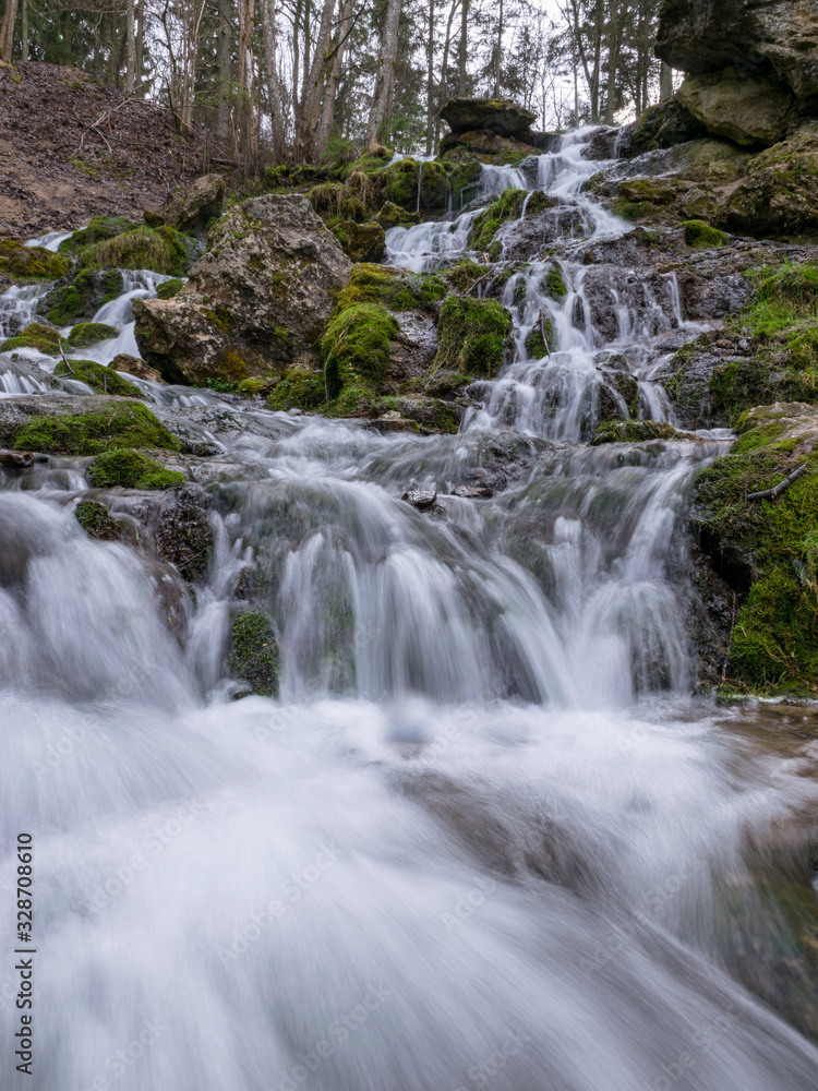 A stream of water flowing over rocks and creating a waterfall effect. A stream of water flowing over rocks and creating a waterfall effect.