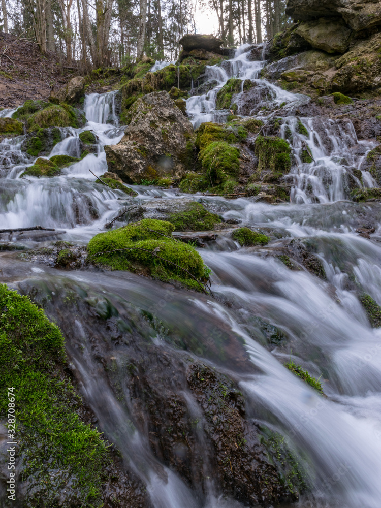 A stream of water flowing over rocks and creating a waterfall effect.