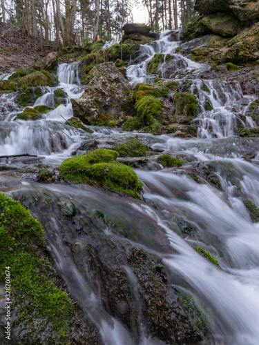 A stream of water flowing over rocks and creating a waterfall effect.