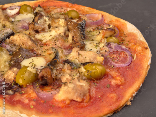 Pizza with sardines, tomatoes and olives on a thin dough.On black background