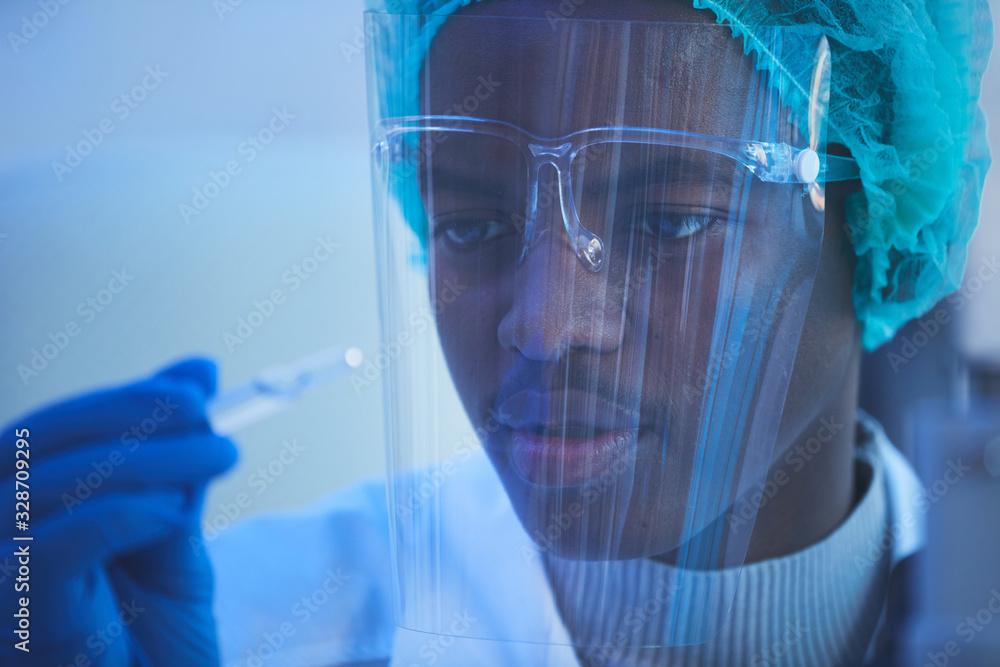 Horizontal close up portrait of young African American male laboratory scientist holding ampoule with new vaccine he developed Horizontal close up portrait of young African American male laboratory scientist holding ampoule with new vaccine he developed