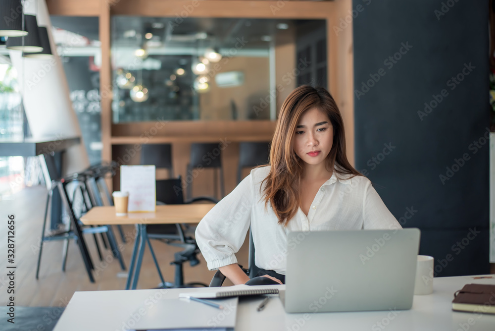 Young asian businesswoman are tired and not happy working with a laptop computer in the office Young asian businesswoman are tired and not happy working with a laptop computer in the office