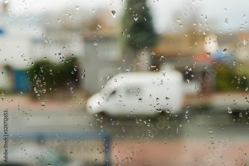 Widok na ulicę przez okno pokryte kroplami deszczu.