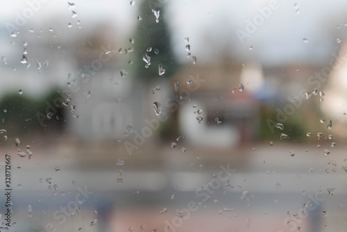 Widok na ulicę przez okno pokryte kroplami deszczu. © boguslavus
