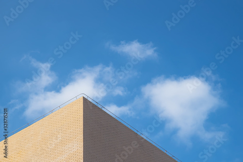 Part of the elevation of the building is in the background of blue sky and white clouds