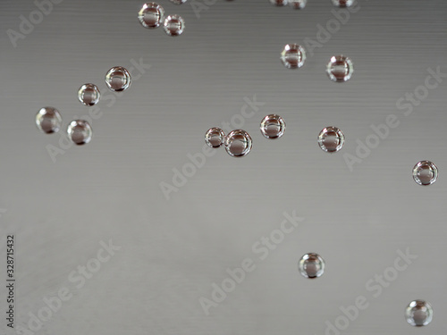 closeup of air bubbles on water glass with gray background