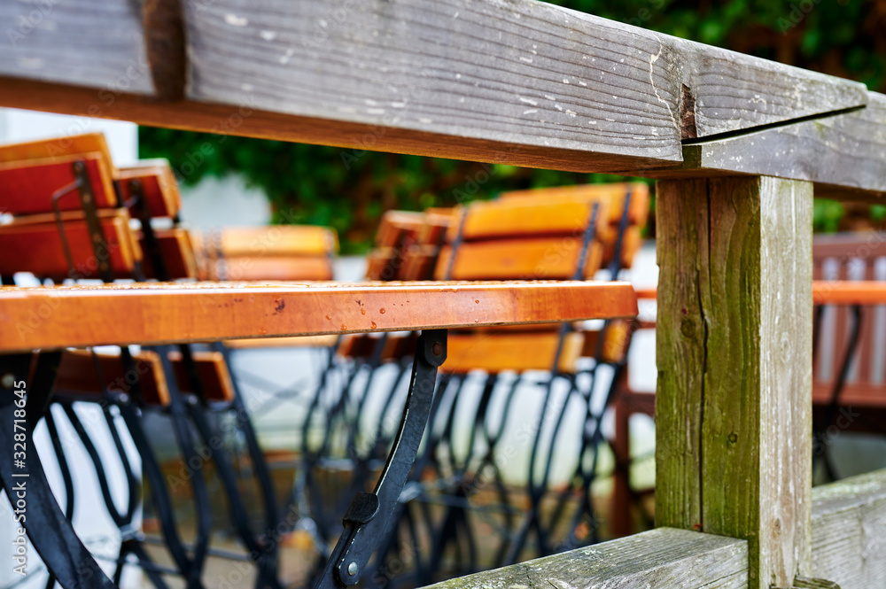 Looking through a wooden terrace railing to tables and folded chairs of a restaurant in bad weather. Looking through a wooden terrace railing to tables and folded chairs of a restaurant in bad weather.