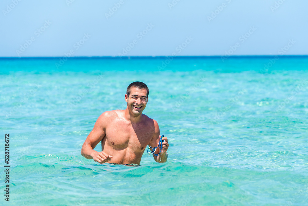 Attractive young caucasian man in the sea , wearing glasses. Summer vacation concept.