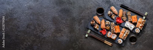 Panel kuchenny z motywem sushi rolls with rice and fish, soy sauce on a dark stone background