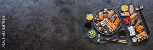 Obraz  z motywem sushi rolls with rice and fish, soy sauce on a dark stone background