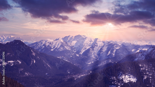 panoramic view of snowy mountains and rays of the sun