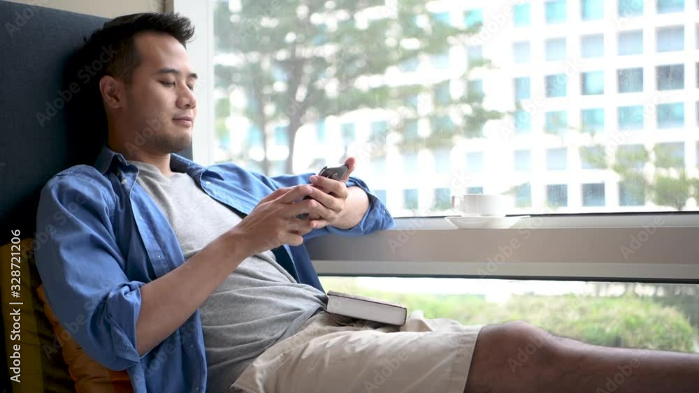 Young man using smartphone while sitting on sofa at home .