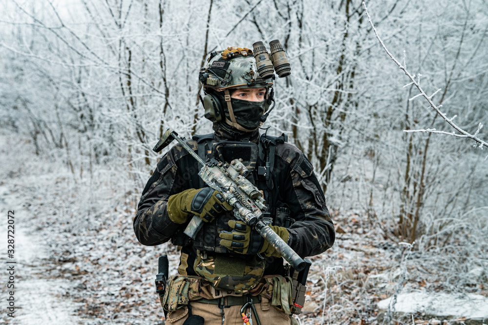 Airsoft man in black camouflage uniform and short machinegun with optical sight. Soldier in the winter forest. Horizontal photo side view. Airsoft man in black camouflage uniform and short machinegun with optical sight. Soldier in the winter forest. Horizontal photo side view.