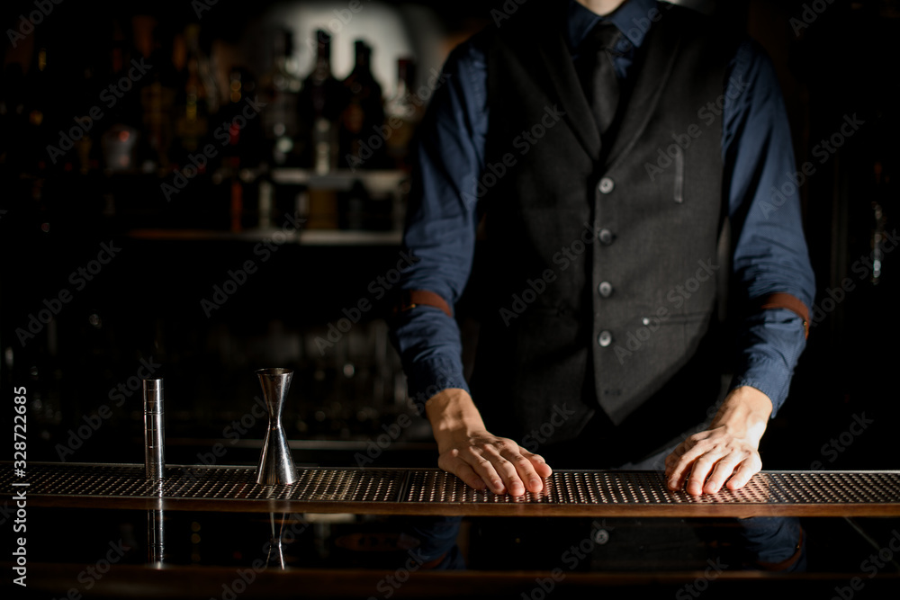 Bartender in blue shirt is standing behind the bar.