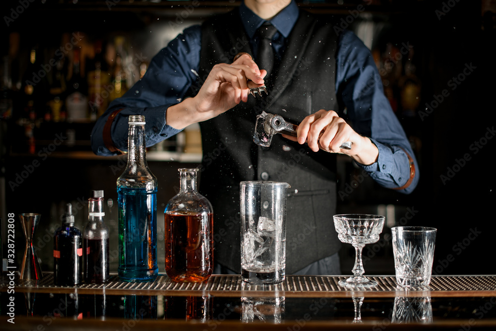 Barman splits pieces of ice to make a cocktail. Barman splits pieces of ice to make a cocktail.