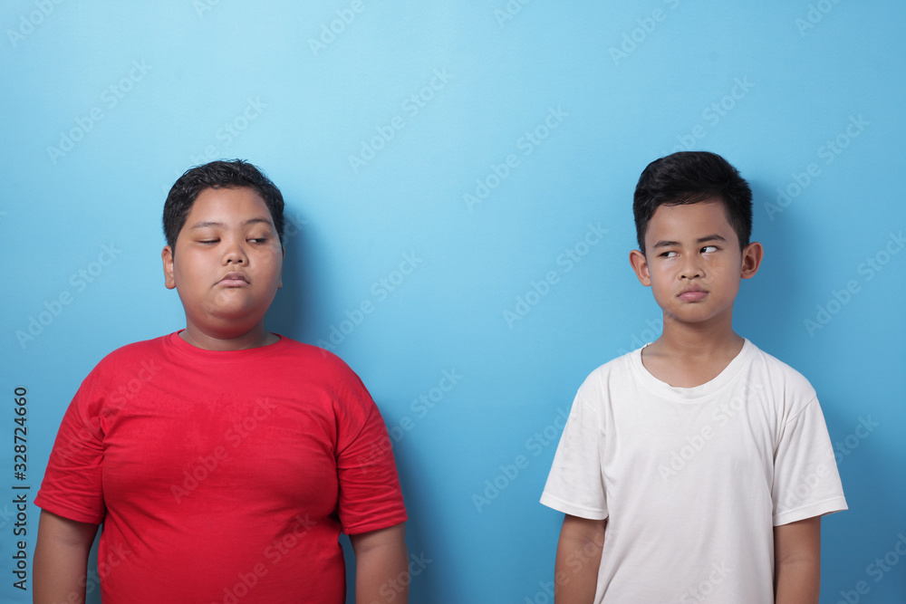 Two Asian boys looking each other with cynical angry look Two Asian boys looking each other with cynical angry look