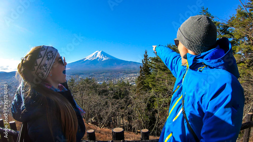 Photography A couple standing on the hilltop above Chureito Pagoda, Japan and pointing at Mt Fuji in the back