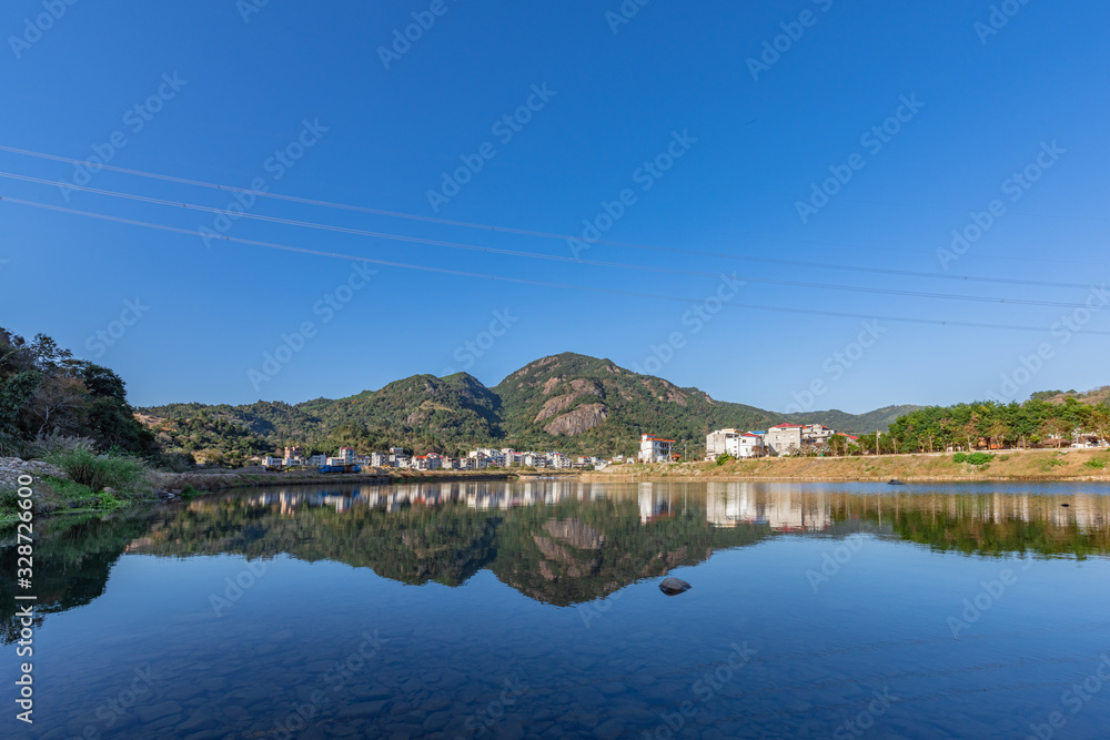 Fototapeta premium Under the blue sky, the rural lake reflects the landscape