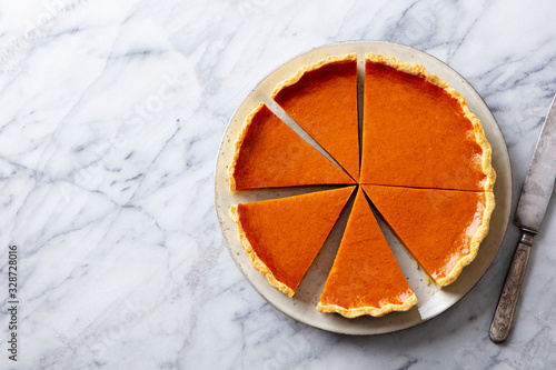 Pumpkin pie on a plate. Marble background. Copy space. Top view.