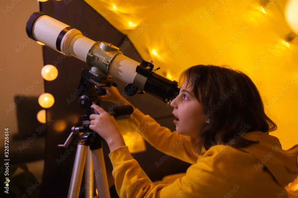 Small girl using telescope at home living room in a tent. Small girl using telescope at home living room in a tent.