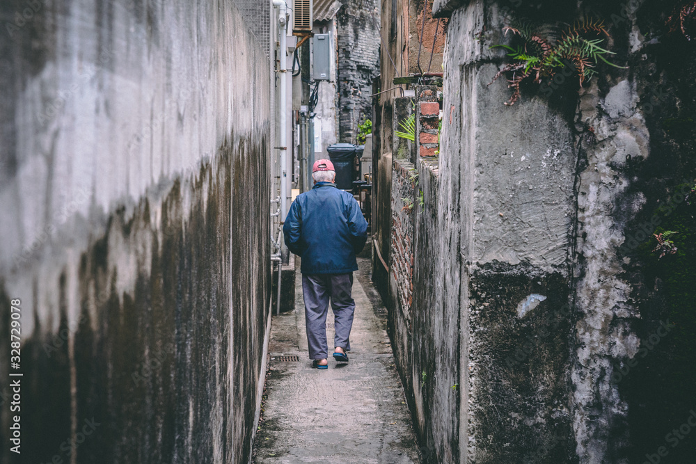 Old man walking between 2 old walls in a old village