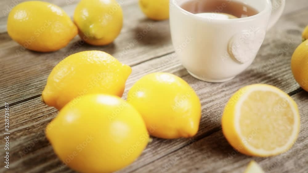 Cup of black tea with lemon slice and plenty of lemons around on grey wooden table in 4K VIDEO. Warm drink infusion for cold fall and winter days. Concept of prevention for flu cold with Vitamin C Cup of black tea with lemon slice and plenty of lemons around on grey wooden table in 4K VIDEO. Warm drink infusion for cold fall and winter days. Concept of prevention for flu cold with Vitamin C