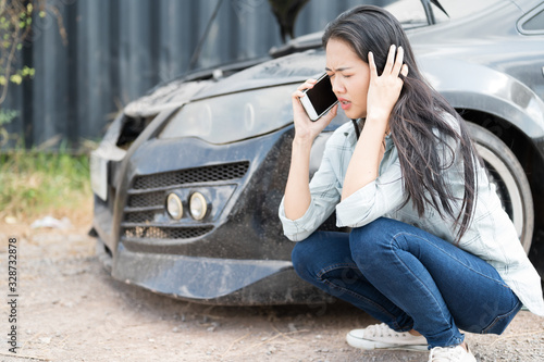Asian young woman are stressed  and calling car insurance.Broken down car while traveling.Black long hair woman talking on cellphone after car breakdown trouble problem mechanic. © arcyto