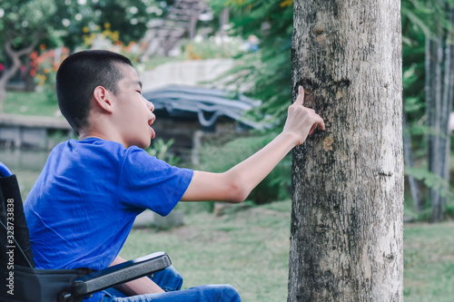 Disabled child on wheelchair is playing, learning and exercise in the outdoor city park like other people,Lifestyle of special child,Life in the education age of children,Happy disability kid concept.