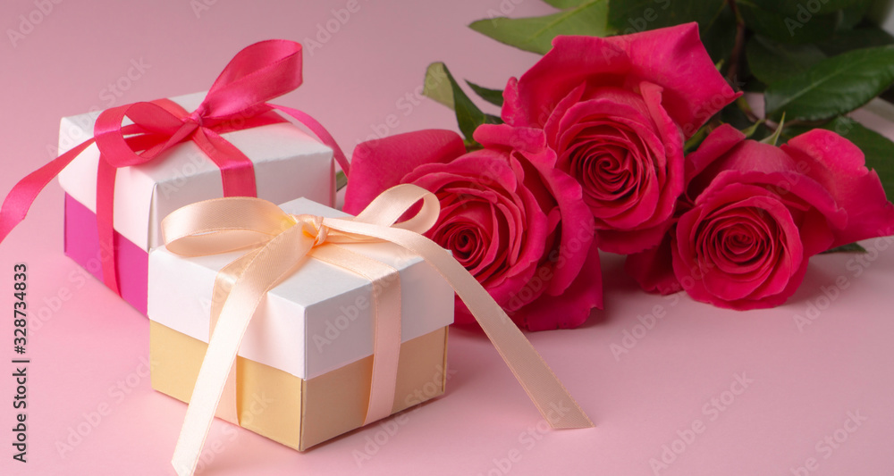gift boxes multicolored with satin ribbons and three pink floyd roses on a pink background gift boxes multicolored with satin ribbons and three pink floyd roses on a pink background