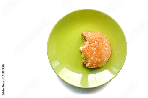 Top eye view of Bite a half of delicious yummy layer burger chicken pepper, spicy pork, egg, cheese, mayonnaise, lettuce fast food in the green plate on a white table background at the kitchen counter