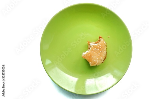 Top eye view of Bite a half scrap of delicious yummy layer burger chicken pepper, spicy pork,egg,cheese, mayonnaise, bun, lettuce in the green plate on a white table background at the kitchen counter.