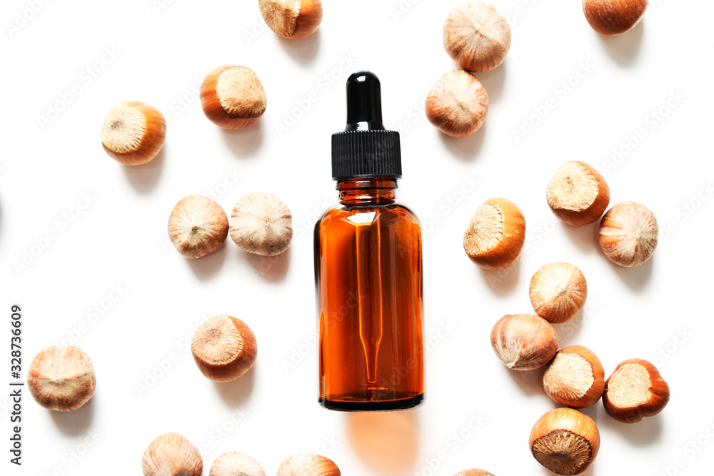 Glass bottle for cosmetics, natural medicine, essential oils or other liquids on a white background, with a nut. Top view. Organic