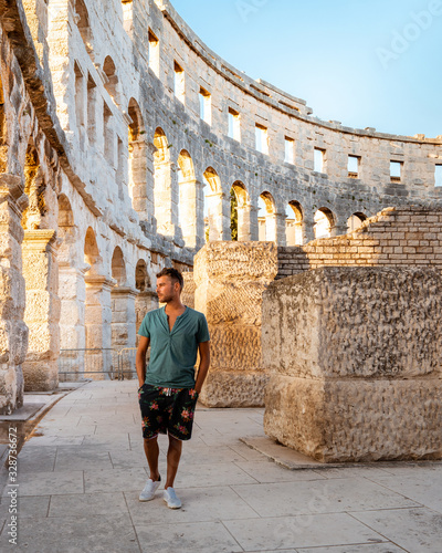 Pula Croatia , summer evening in front of Ampitheatrhe arena , young men walking at Pula Croatia arena