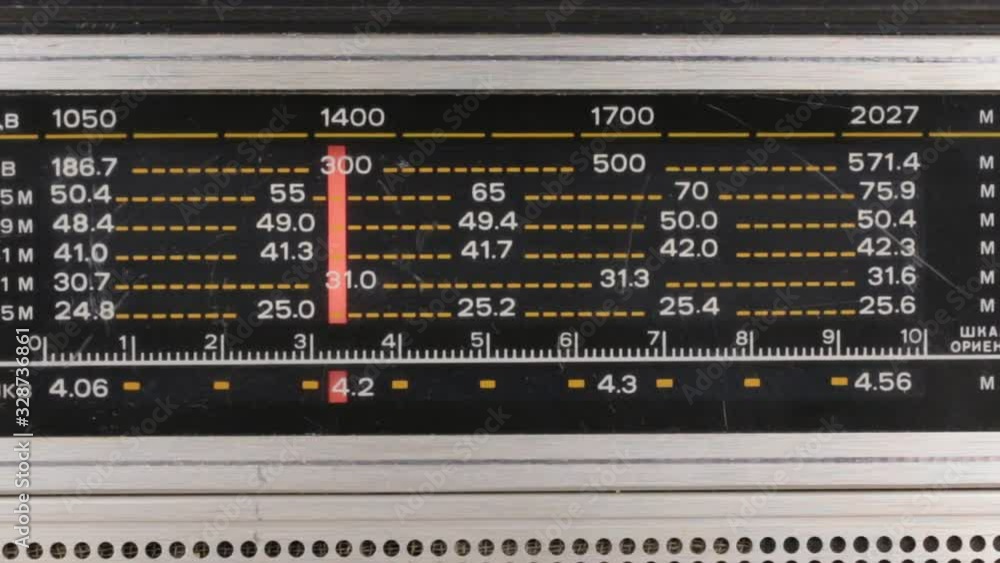 Tuning the frequency of the radio station on the old radio. The red arrow moves on a scale with numbers. Tuning the frequency of the radio station on the old radio. The red arrow moves on a scale with numbers.